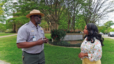 Denella Ri’chard discusses the Little Rock Nine with Ranger Randy during her visit to the Little Rock Central High School National Historic Site in Arkansas. The site was among those featured in her Black History Month TV special.